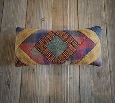 a colorful pillow sitting on top of a wooden floor next to a wood plank wall