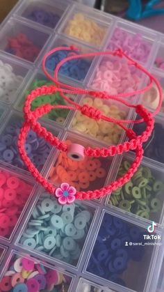 the beads are in plastic containers with pink string on them and one bead has a flower