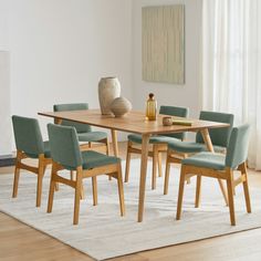 a dining room table with chairs and a vase on the rug in front of it