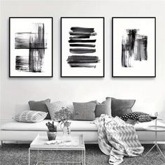 three black and white paintings hanging on the wall above a couch in a living room