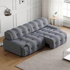 a gray couch sitting on top of a hard wood floor next to a white rug