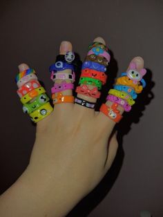 a hand with five different colored bracelets on it's fingers and one is holding the other