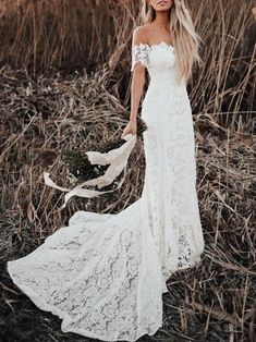 a woman in a white dress standing in tall grass