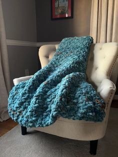 a blue crocheted blanket sitting on top of a chair