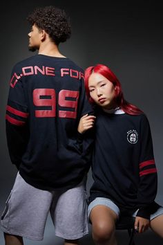 a young man and woman are posing for the camera, both wearing black shirts with red numbers on them