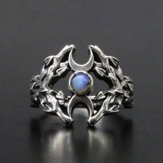 This Witch Ring is crafted from 925 silver and features a stunning moonstone. Weighing 7 grams, this ring is both elegant and powerful. Materials 925 sterling silver Moonstone Weight: 7 grams Symbolism The ring showcases the Triple Moon symbol - a full moon framed by two crescents, representing the waxing and waning phases. On the sides of the ring, you'll find beautiful twig weaving, enhancing its natural and mystical appearance. The central symbol, the Triple Goddess, embodies the three aspect Twig Weaving, Sailor Moon Ring, Norse Ring, Moon Stone Ring, Witch Ring, Forest Ring, Ring Magic, Moon Phase Ring, Moon Symbol