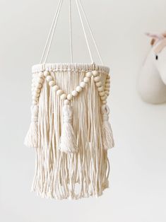 a white hanging mobile with tassels and beads