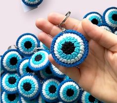 a hand holding a blue and white keychain with an evil eye on it