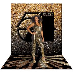 a woman standing in front of a backdrop with gold coins on it and the number 5