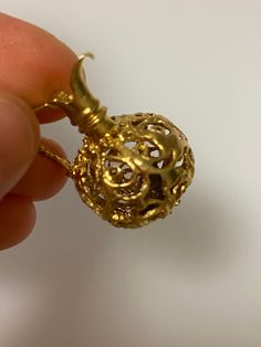 a person is holding a gold pendant in their hand