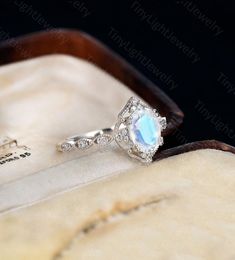 an engagement ring with a blue topazte surrounded by diamonds in a wooden box