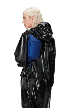 a woman with blonde hair wearing a black raincoat and blue backpack on her back