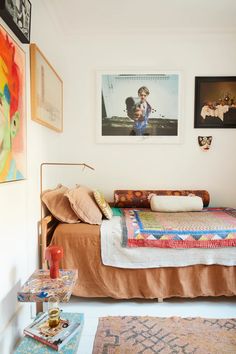 a bed sitting in a bedroom next to two pictures on the wall and rugs