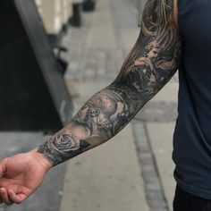 a man with a tattoo on his arm holding something in his hand while walking down the street