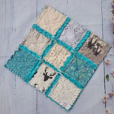 a close up of a patchwork quilt on a wooden surface with flowers in the background