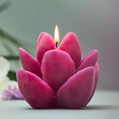 a small pink candle sitting on top of a white table next to some purple flowers