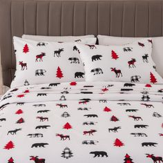 a bed with white sheets and black and red moose print on it, next to a brown headboard