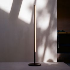 a lamp that is on top of a table next to a wall with a shadow cast on it