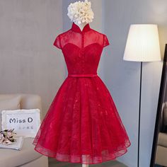 This exquisite vintage-inspired red lace cheongsam dress is the perfect blend of traditional elegance and modern sophistication. The design showcases a classic high-neck Mandarin collar and delicate cap sleeves, accentuating a structured, feminine silhouette. The bodice is tailored with precision, featuring a sweetheart neckline beneath sheer lace fabric that is adorned with beautiful button detailing along the front. A slim satin belt cinches the waist, giving the dress an elegant, flattering s Cap Sleeve Fitted Lace Dress, Fitted Lace Dress With Cap Sleeves, Fitted Cap Sleeve Lace Dress, Fitted Lace Bodice Dress For Banquet, Fitted Lace Evening Dress With Short Sleeves, Fitted Lace Bodice Dress With Cap Sleeves, Fitted Cap Sleeve Dress With Lace Bodice, Fitted Knee-length Lace Dress For Prom, Fitted Lace Knee-length Dress For Prom