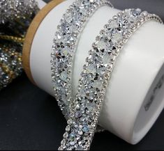 three bracelets are sitting on top of a roll of tape and some glitter is next to it