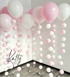 pink and white balloons floating from the ceiling in a room with grey wood flooring