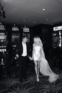 a man and woman standing next to each other in front of slot machines