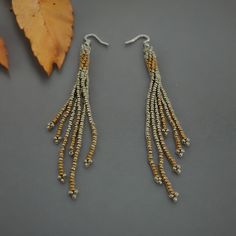 Drape yourself in elegance with these captivating Seed Bead Long Fringe Earrings that effortlessly blend gold and silver hues to form a stunning accessory piece. The intricate beadwork showcases a delicate fusion of colors, making them a versatile and chic addition to any outfit. As the elongated fringe gently sways with your every movement, these earrings exude a sense of grace and sophistication. Crafted with precision and attention to detail, these earrings boast a timeless design that complements various styles from casual to evening wear. The combination of seed beads in gold and silver tones creates a mesmerizing contrast that catches the light and adds a subtle sparkle to your look. Perfect for autumn and fall, these long fringe earrings are a celebration of artistry and craftsmansh Beaded Tassel Earrings With Round Beads For Parties, Bohemian Silver Earrings With Gold Beads, Party Beaded Earrings With Silver Round Beads, Party Tassel Earrings With Round Beads, Silver Dangle Earrings With Gold Beads, Elegant Tassel Earrings With Colorful Beads For Party, Long Fringe, Long Fringes, Earrings Beaded