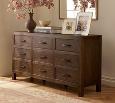 a wooden dresser with flowers and pictures on top