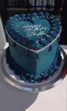 a blue heart shaped cake sitting on top of a table