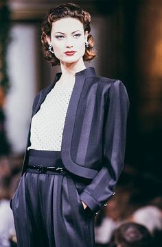 a woman is walking down the runway wearing black and white clothes with pearls on her ear