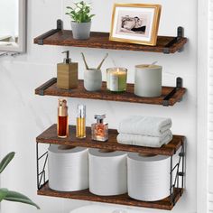 three shelves with towels, candles and other items on them in a white room next to a toilet