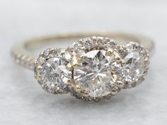 three stone engagement ring with diamonds on the sides and an oval diamond in the middle