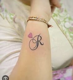 a woman's arm with a tattoo on it that has the letter r and a heart