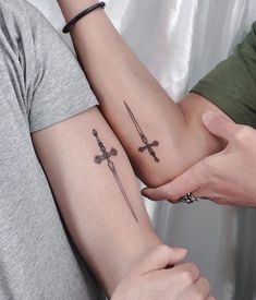 two people with matching tattoos on their arms holding onto each other's wrists