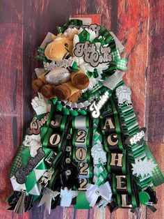 a teddy bear sitting on top of a green and white ribbon with the words happy new year