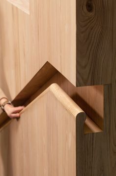 a person holding a piece of wood in front of a wooden wall with an arrow on it