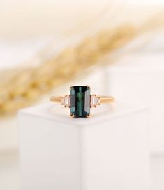 an emerald colored stone ring sitting on top of a white box