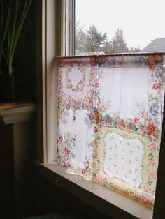 a window sill with a flowered curtain hanging from it's side, next to a potted plant