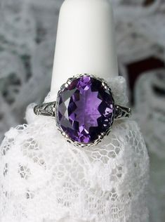 "Natural Purple Amethyst Ring Description Edward Design#70 (smaller version) MADE TO ORDER Inspired by Edwardian jewelry of the early 1900s, I now offer this lovely Antique reproduction ring in sterling silver. This gorgeous ring is set with a stunning 3.32ct Natural purple amethyst gemstone. This genuine amethyst has excellent color and clarity. The oval cut amethyst is 12mm (1/2th of an inch) Long by 10mm Wide (3/8th\"). The ring sits 6mm off the finger. The inside of the band s marked 925 for Classic Wedding Gemstones With Diamond Cut, Classic Oval Amethyst Ring With Accent Stones, Oval Amethyst Ring With Accent Stones For Anniversary, Classic Oval Amethyst Ring With Prong Setting, Classic Wedding Gemstones With Accent Stones, Classic Oval Gemstones For Wedding, Oval Amethyst Ring With Diamond Cut, Classic Amethyst Ring For Wedding, Oval Diamond Cut Amethyst Ring