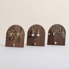 three wooden earring holders with different designs on them, one is gold and the other is silver