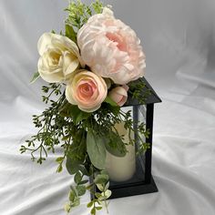 a vase filled with flowers on top of a white tablecloth covered floor next to a candle