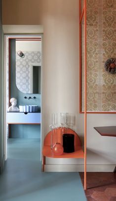 an orange shelf in the middle of a room next to a small table and chair