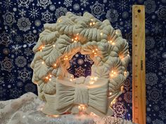 a christmas wreath with lights on it next to a ruler and snowflake background