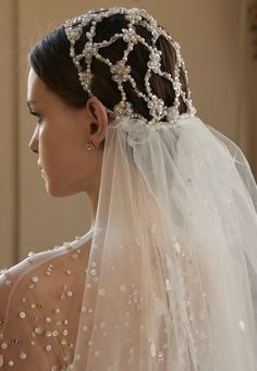 a woman wearing a wedding veil with pearls on it