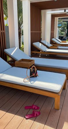 two pairs of pink flip flops sitting on top of a wooden deck next to lounge chairs