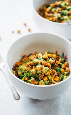 two white bowls filled with food on top of a table