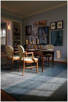 a dining room table with chairs and pictures on the wall