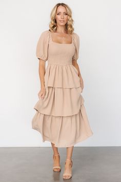 Indulge elegance and grace with every step in this dress! Mid-weight textured material Neutral taupe color Stunning square neckline Short sleeves with elastic cuffs Smocked bodice allows for great stretch Cascading tiered midi skirt Fully lined Self and Lining: 100% Polyester Trina is 5'6, cup size 32D, size 2 and is wearing size S Beige Tiered Skirt Dress With Ruffle Hem, Fitted Beige Tiered Midi Dress, Beige Tiered Gathered Skirt, Beige Tiered Ruffle Midi Dress, Beige Non-stretch Tiered Skirt, Tiered Midi Skirt, Baltic Born, Couples Outfit, Chic And Elegant