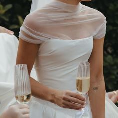 the bride is holding two champagne flutes in her hand