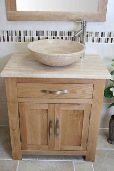 a bathroom sink sitting under a mirror next to a wooden cabinet and tiled flooring